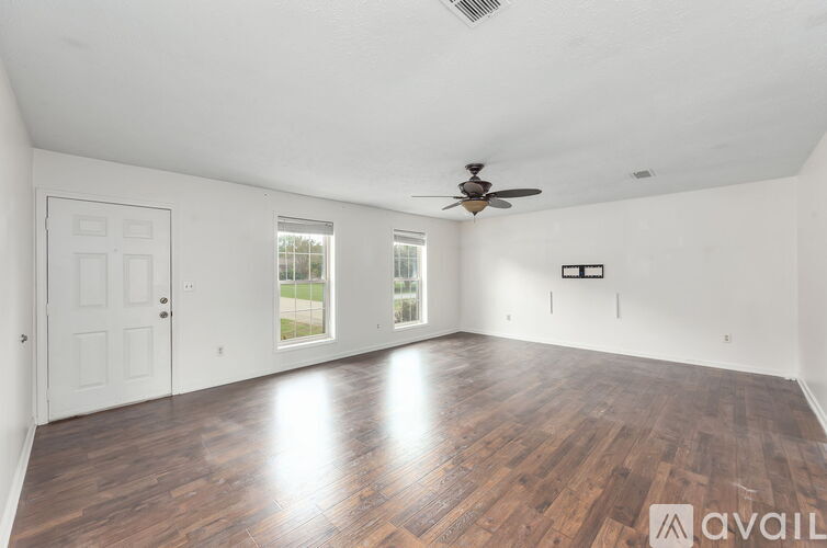 A spacious room with wooden floors and a ceiling fan.