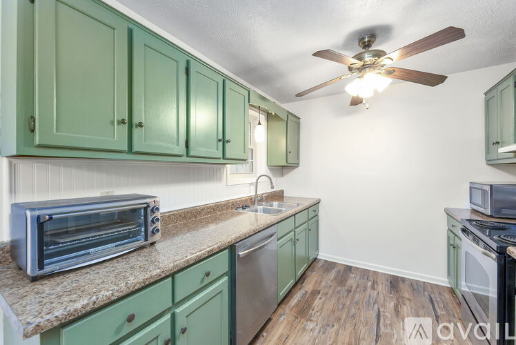 A kitchen with green cabinets and a fan on the ceiling.