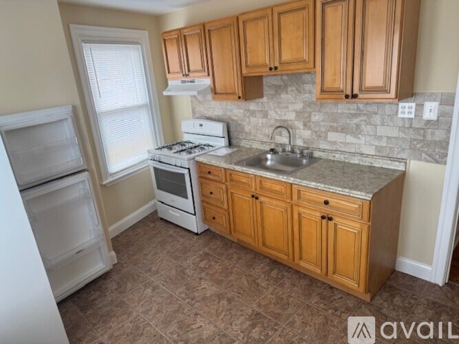 A kitchen with wooden cabinets and a stone backsplash.