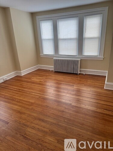 A room with wooden floors and a window with blinds.