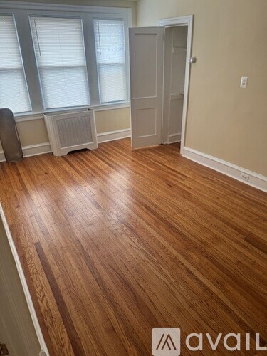 A room with wooden floors and a window with blinds.