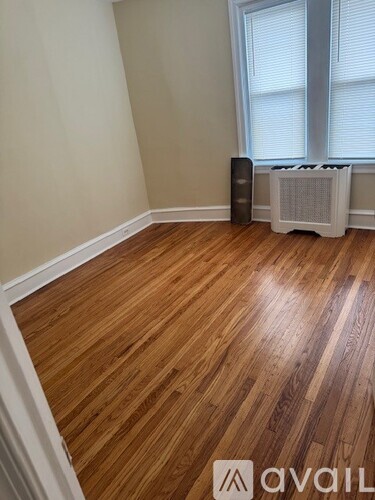 A room with wooden flooring and a window with blinds.
