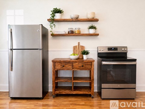 A modern kitchen with a stainless steel refrigerator, a wooden table with a cutting board, and a black oven.