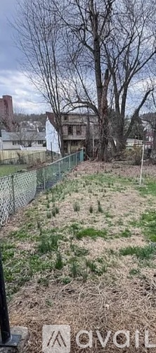A fenced area with a tree and a building in the background.