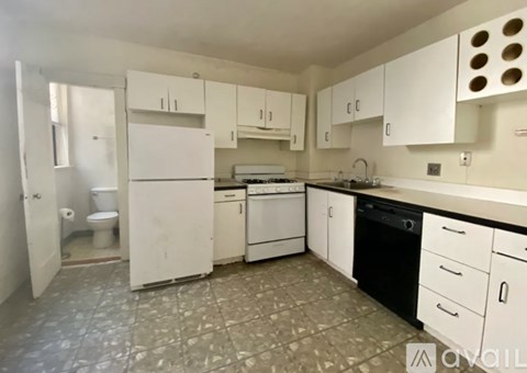 A kitchen with white cabinets and a tiled floor.