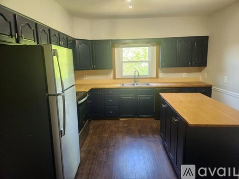 A kitchen with black cabinets and a wooden countertop.