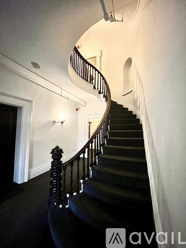 A staircase with a black carpet and wooden balusters.