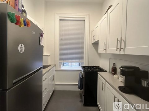 A kitchen with a black stove top oven and a fridge with magnets on it.