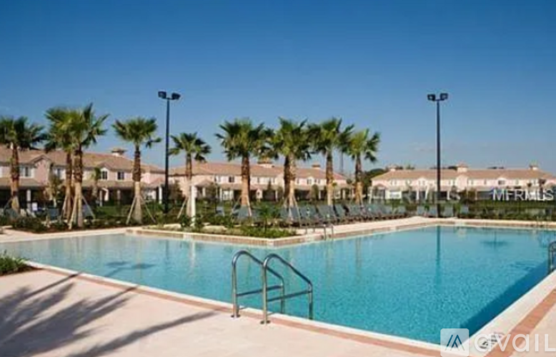 A swimming pool surrounded by palm trees and apartment buildings.