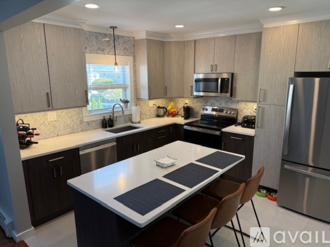 A kitchen with a table and chairs in the foreground and a refrigerator, microwave, and oven in the background.