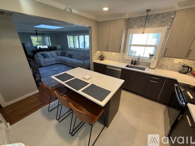 A kitchen with a table and chairs in the foreground and a living room with a couch and a television in the background.