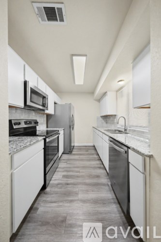 A modern kitchen with white cabinets and stainless steel appliances.