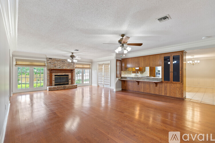 A spacious living room with wood flooring and a fireplace.