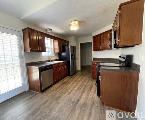 A kitchen with wooden cabinets and a black refrigerator.