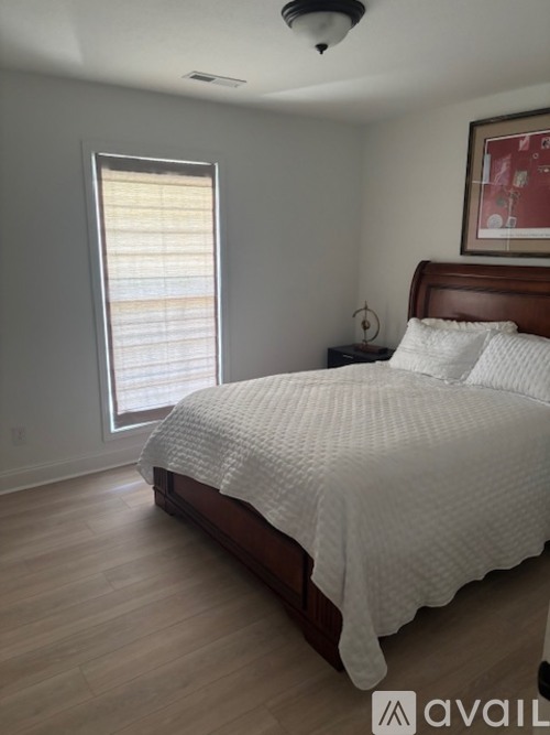 A bedroom with a large bed and a window with blinds.