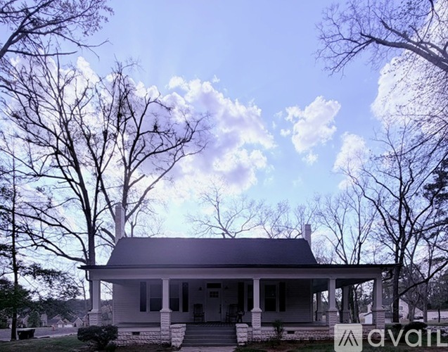 A house with a porch and a chimney is surrounded by trees.