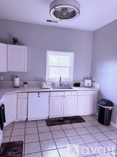 A kitchen with white cabinets and a window above the sink.