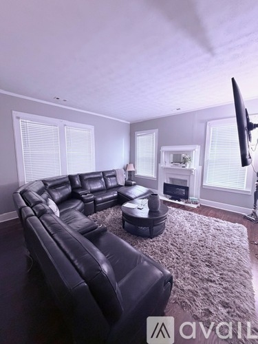 A black leather sofa in a living room with a flat screen TV mounted on the wall.
