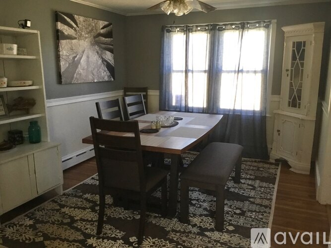 A dining room with a table set for two and a painting on the wall.
