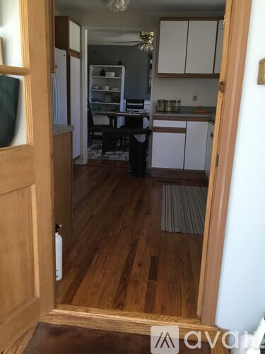 A kitchen with white cabinets and a wooden floor.