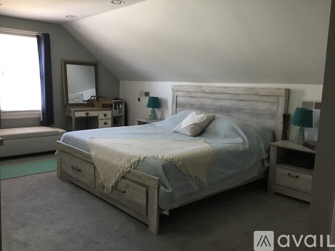 A bedroom with a bed, nightstand, and a dresser with a mirror.