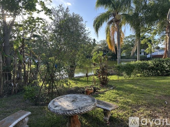 A backyard with a table and bench near a body of water.