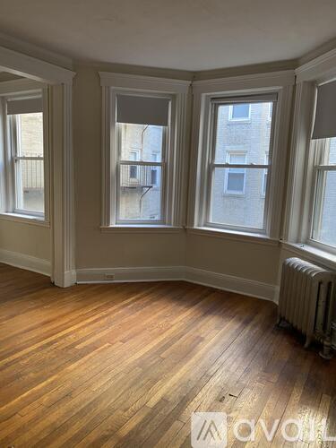 A room with wooden floors and three windows.
