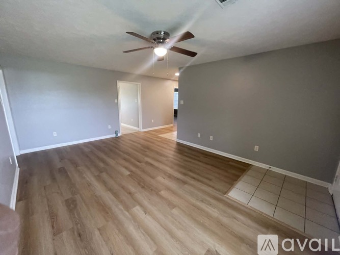 A room with a ceiling fan and wooden flooring.