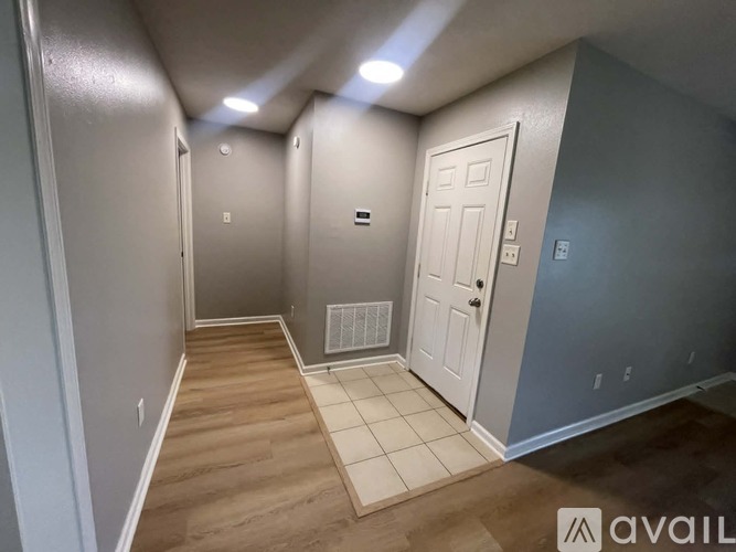 A hallway with a white door and a tiled floor.
