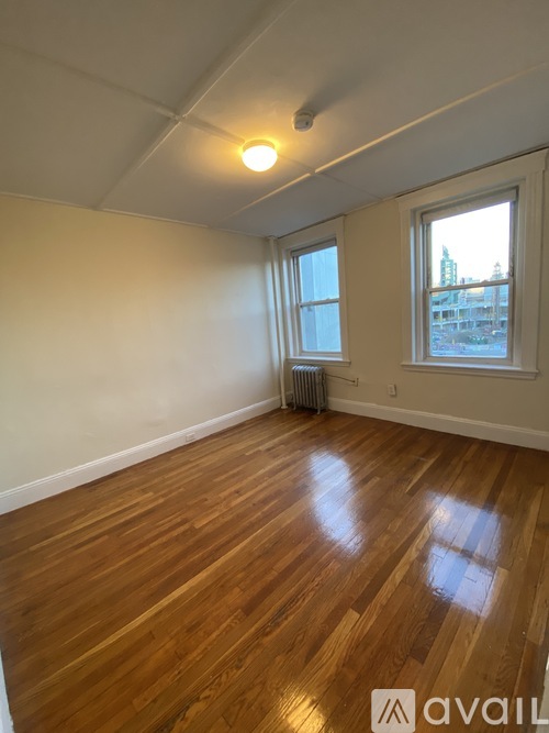 A room with wooden floors and a window overlooking a cityscape.