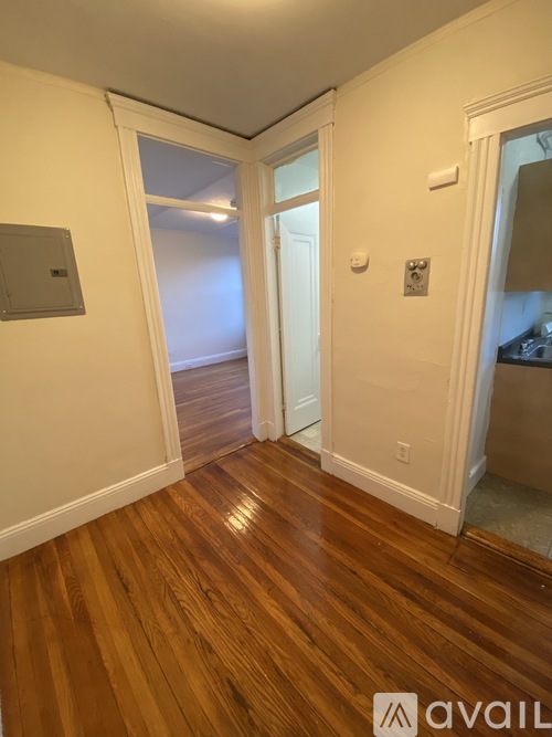 A hallway with wooden floors and white walls.
