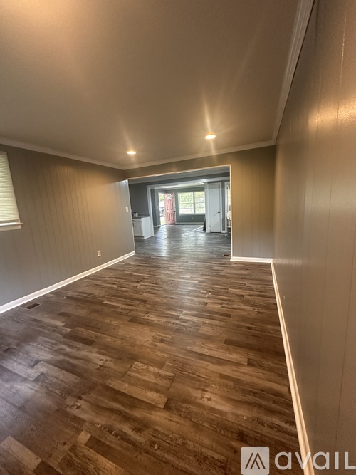 A long hallway with wood flooring and a door at the end.