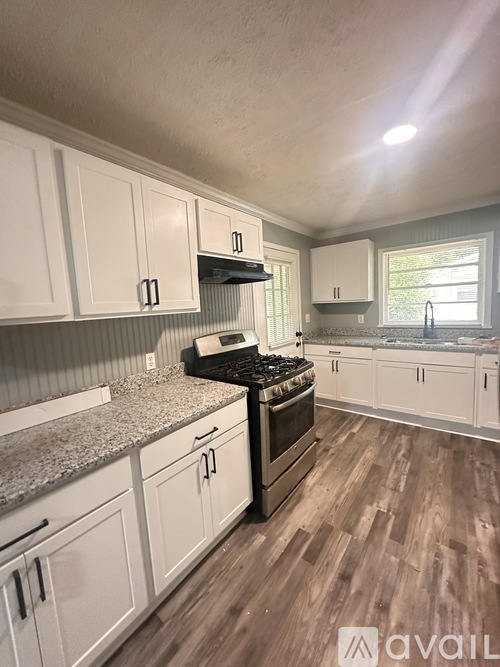 A kitchen with white cabinets and a granite countertop.