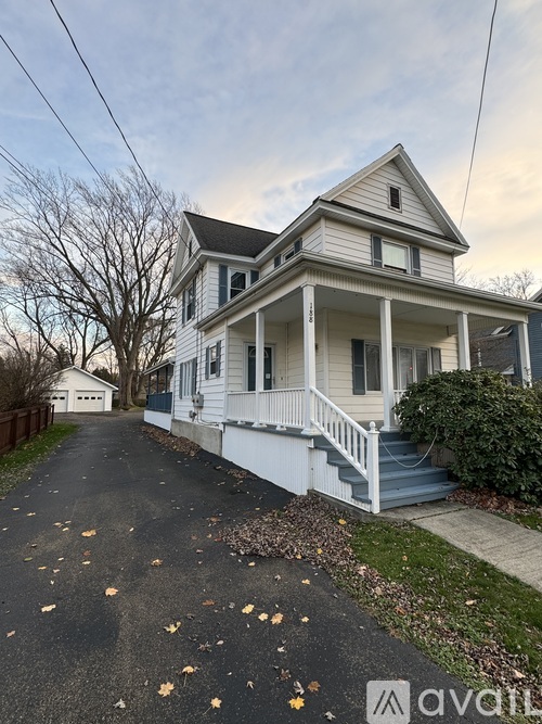A white two-story house with a front porch and a driveway.