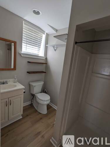A bathroom with a toilet, sink, and wooden floors.