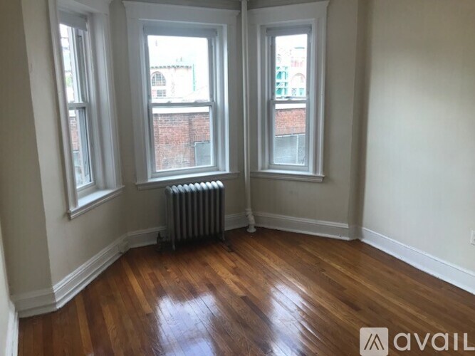 A room with wooden floors and two windows.