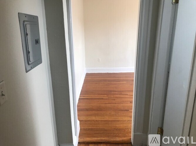 A hallway with a wooden floor and white walls.