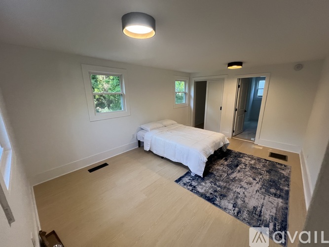 A bedroom with a bed, a rug, and a window.