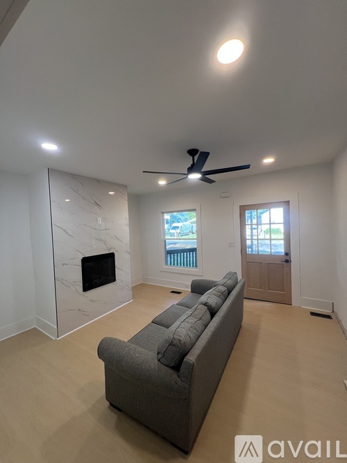 A living room with a grey couch and a marble fireplace.