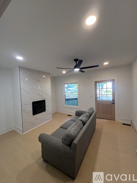 A living room with a grey couch and a marble fireplace.