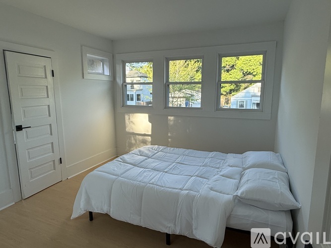 A bedroom with a large bed and a window overlooking a tree.