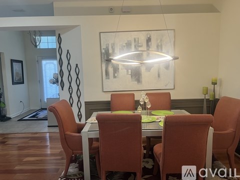 A dining room with a table set for four and a large abstract painting on the wall.