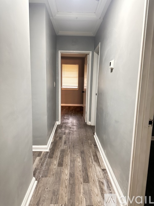 A long hallway with wood floors and white walls.