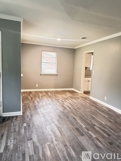 A room with wooden flooring and a window with blinds.