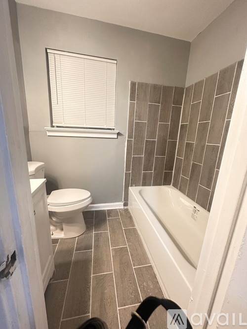 A bathroom with a toilet, tub, and tiled walls.