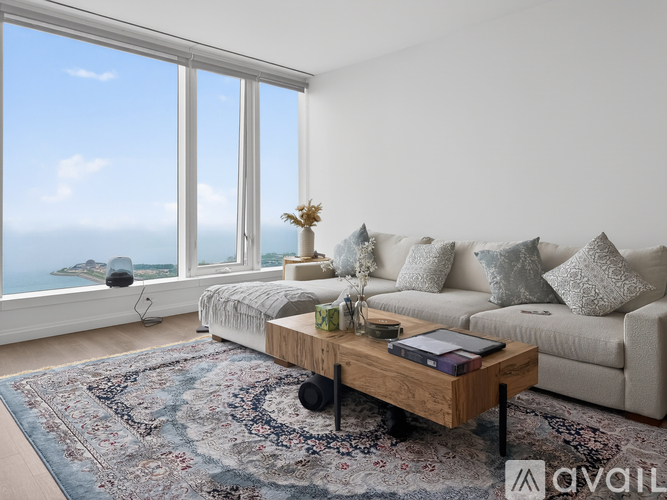 A living room with a couch, a coffee table, and a large window overlooking the ocean.