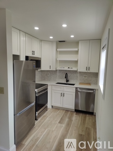 A kitchen with white cabinets and a stainless steel refrigerator.