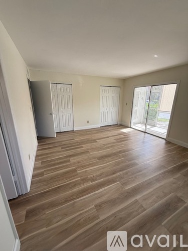 A spacious room with wooden flooring and two doors.