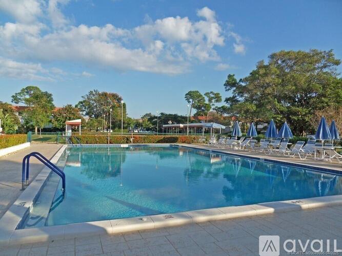 A large outdoor swimming pool with a blue sky and clouds in the background.