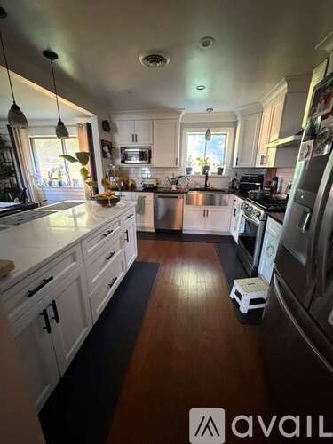 A kitchen with white cabinets and a wooden floor.